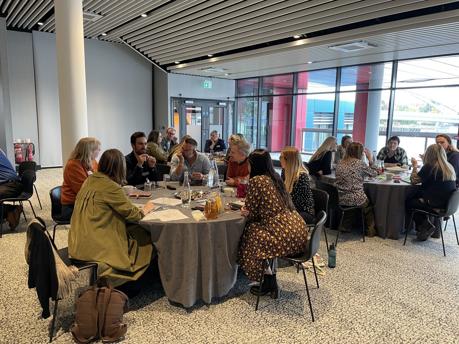 A cross-functional group working together around tables during a process design session